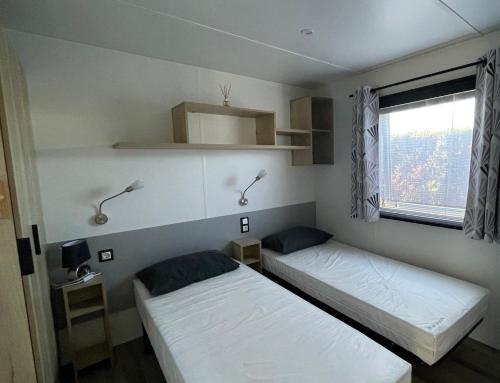 deux lits dans une petite pièce avec une fenêtre dans l'établissement Large 2 bedroom mobile home Cc441 Siblu Les Charmettes, aux Mathes