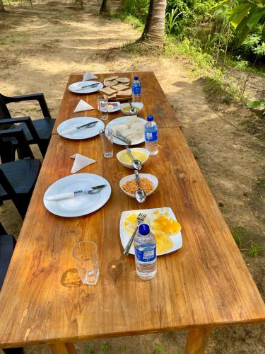 a wooden table with plates of food and water bottles at coconut camp udawalawe in Dematapelessa