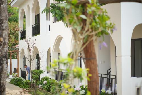 a man walking down a sidewalk in front of a white building at An Home - Garden Homestay in Plei Brel (2)