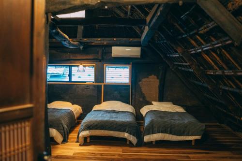 a group of four beds in a room at ゲストハウス紡 in Ubaguchi