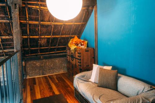 a living room with a couch and a blue wall at ゲストハウス紡 in Ubaguchi