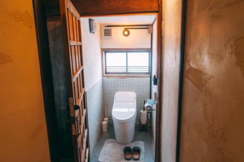 a small bathroom with a toilet and a window at ゲストハウス紡 in Ubaguchi