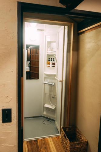 a refrigerator in a room with a door open at ゲストハウス紡 in Ubaguchi
