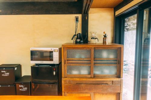 a kitchen with a microwave and a cupboard with a microwave at ゲストハウス紡 in Ubaguchi