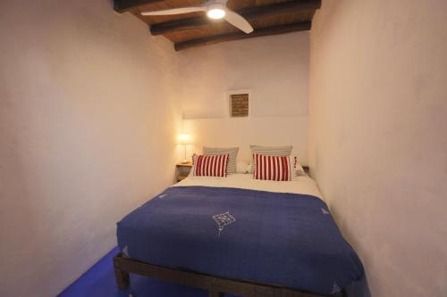 a bedroom with a bed with blue sheets and red pillows at DAR MUKTAB in Chefchaouene
