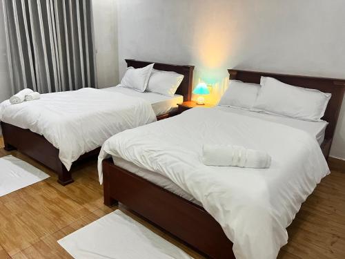 a bedroom with two beds with white sheets at The Leaf Hotel SR in Phumĭ Réach Born