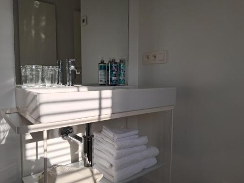 a bathroom with a sink and a pile of towels at Het Bed van den Doktoor in Meerhout