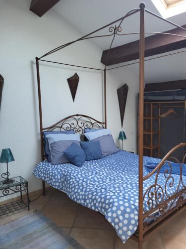 - une chambre avec un lit à baldaquin et des oreillers bleus dans l'établissement Le Gîte des étoiles de la Clape, à Salles-d'Aude