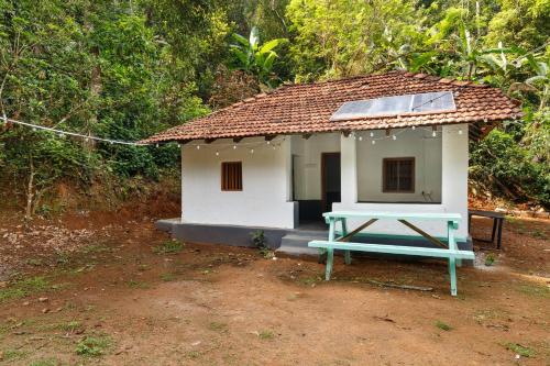 a small house with a blue table in front of it at Underground Hostel By Bilwa Estate in Madikeri