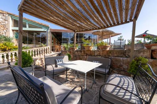 a patio with a table and chairs under a pergola at Finca Hotel Rural Es Turó in Ses Salines