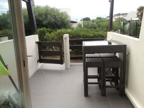 un porche avec une table et des chaises sur un balcon dans l'établissement Studio 7, Port Nature 1 au village naturiste, au Cap d'Agde