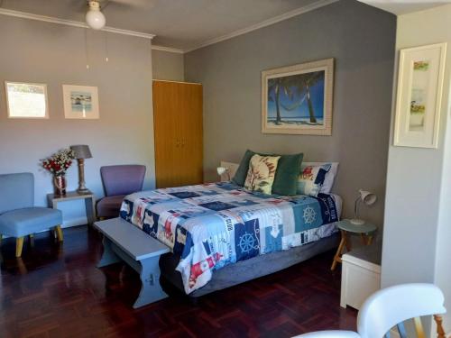 a bedroom with a bed and a table and chairs at Sunshine Cottage in Fish Hoek