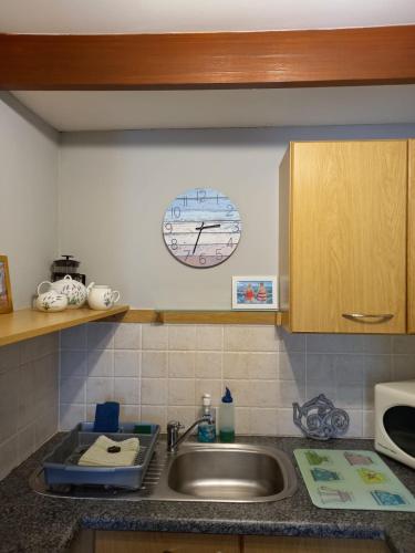 a kitchen counter with a sink and a clock on the wall at Sunshine Cottage in Fish Hoek
