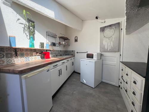 une cuisine avec des armoires blanches et un comptoir dans l'établissement Maison climatisée 4 chambres terrasse 3 kms plage, à Saint-Laurent-de-la-Salanque