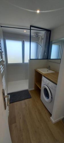 - une buanderie avec un lave-linge et un miroir dans l'établissement Bel appartement avec terrasse et sa petite vue mer Kerroc'h, à Ploemeur