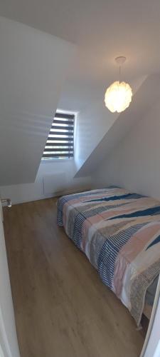 une chambre avec un lit et une lumière au plafond dans l'établissement Bel appartement avec terrasse et sa petite vue mer Kerroc'h, à Ploemeur