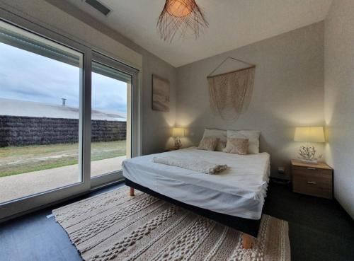 une chambre avec un lit et une grande fenêtre dans l'établissement Belle villa familiale climatisée avec jardin clos, à La Teste-de-Buch
