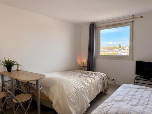 une chambre avec deux lits et une table et une fenêtre dans l'établissement Studio Strasbourg Proche Tram, à Strasbourg