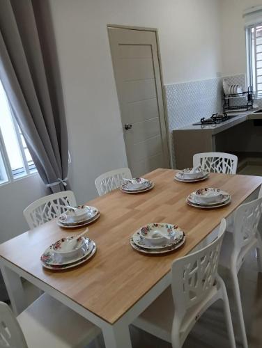 a wooden table with white chairs and plates on it at D'Impian Umbai Homestay EPL, PS4, BBQ in Merlimau