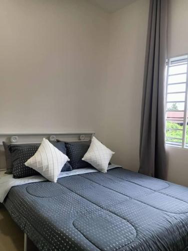 a bedroom with a bed with pillows and a window at D'Impian Umbai Homestay EPL, PS4, BBQ in Merlimau