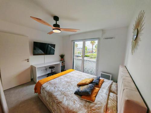une chambre avec un lit et un ventilateur de plafond dans l'établissement Pearl Beach - Rooftop Pool Seaside, à Villeneuve-Loubet