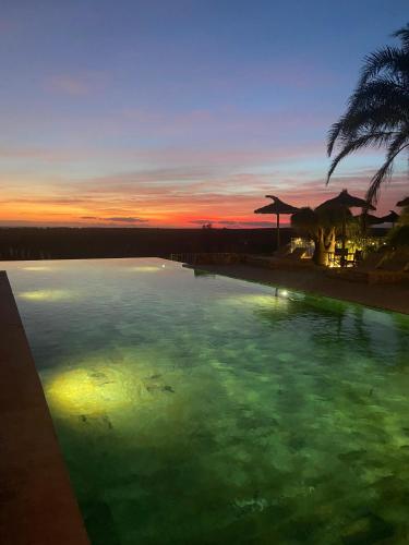 a pool of green water with a sunset in the background at Finca Hotel Rural Es Turó in Ses Salines
