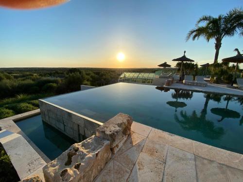 a swimming pool with a sunset in the background at Finca Hotel Rural Es Turó in Ses Salines