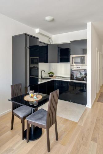 Una cocina con una mesa y dos sillas y una cocina con gabinetes negros. en Studio apartment, en Bar