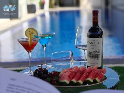 a table with a bottle of wine and a plate of fruit at Royal Water Villa in Kiryat Ekron