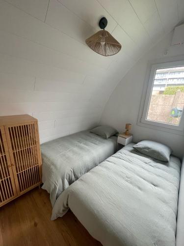 two beds in a room with a window at Ecolodge in Trébeurden