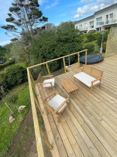 a wooden deck with two chairs and a bench at Ecolodge in Trébeurden