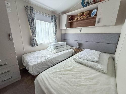 a bedroom with two beds and a window at Beautiful Caravan With Decking At Azure Seas Ref 32060Az in Lowestoft