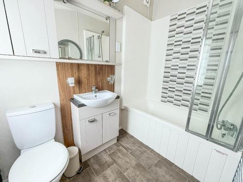 a bathroom with a toilet and a sink and a tub at Beautiful Caravan With Decking At Azure Seas Ref 32060Az in Lowestoft