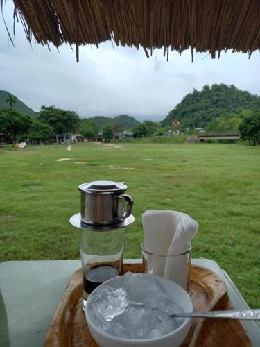 a tray with a drink and a cup on a table with a field at Mai Chau Xanh Bungalow in Mai Chau