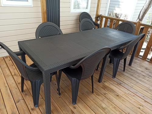 une table et des chaises noires sur une terrasse dans l'établissement Mobil home les violettes - 6 places - Camping du Bosc, à Saint-Cyprien
