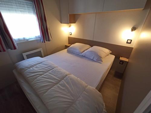 - une chambre avec un lit avec deux oreillers et une fenêtre dans l'établissement Mobil home les violettes - 6 places - Camping du Bosc, à Saint-Cyprien