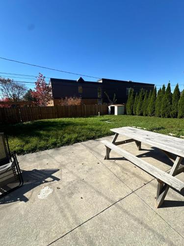 a wooden picnic table sitting on a sidewalk in a yard at Cozy 2 Beds Basement Suite in Windsor