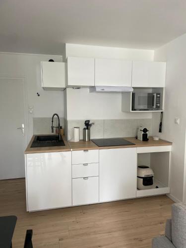 une cuisine blanche avec un évier et un micro-ondes dans l'établissement Charmant T2 rénové à neuf, à Saint-Hilaire-de-Riez
