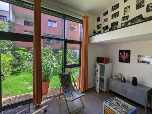 - un salon avec une grande fenêtre et une chaise dans l'établissement Tiny House dans le jardin, à Boulogne-Billancourt
