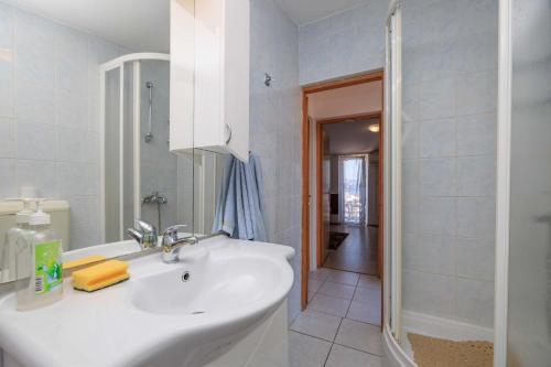 a white bathroom with a sink and a shower at Apartments Kata in Malinska