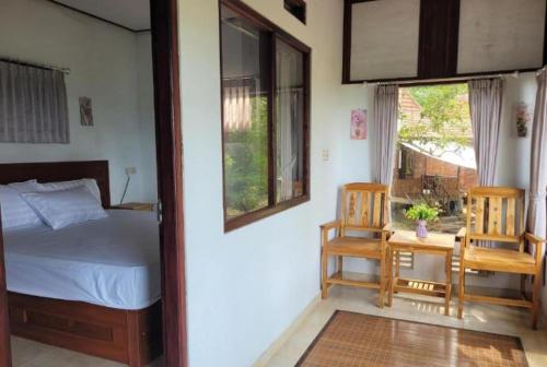 a bedroom with a bed and a table and chairs at D'Langun Bali in Munduk