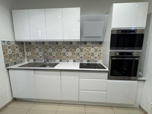 une cuisine avec des armoires blanches et un four à plaques de cuisson dans l'établissement Spacieuse maison, CDG, Astérix, Disney, Paris, à Stains