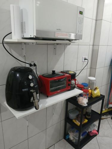 a red microwave on a shelf in a kitchen at Apartamento Estrela da Praia V19 in Mongaguá
