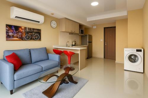 a living room with a blue couch and a washing machine at 1 bedroom Naiharn Beach Condo in Rawai Beach