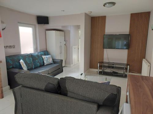 a living room with two couches and a flat screen tv at Langley Guest House Nr Pinewood Studios in Slough