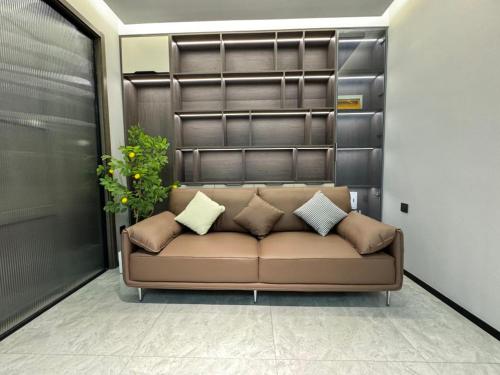 a brown couch in a room with a plant at Today Aparthotel West Lujiazui Shanghai in Shanghai