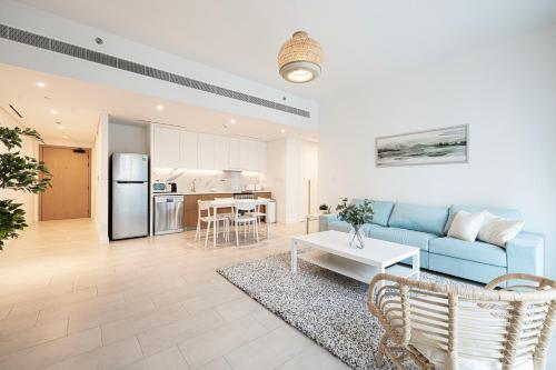 a living room with a blue couch and a kitchen at La Vie, JBR private beach, private parking and pool in Dubai
