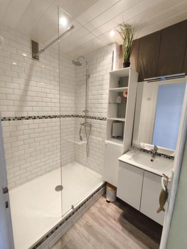une salle de bain blanche avec une douche et un lavabo dans l'établissement Le Rochefort, à Les Sables-dʼOlonne