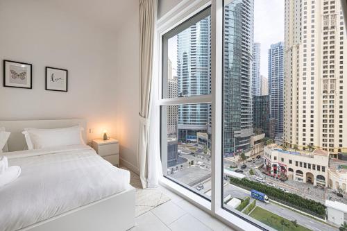 a bedroom with a white bed and a large window at La Vie, JBR private beach, private parking and pool in Dubai