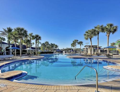 a large swimming pool with palm trees in a resort at New Luxury Townhome near Disney in Orlando